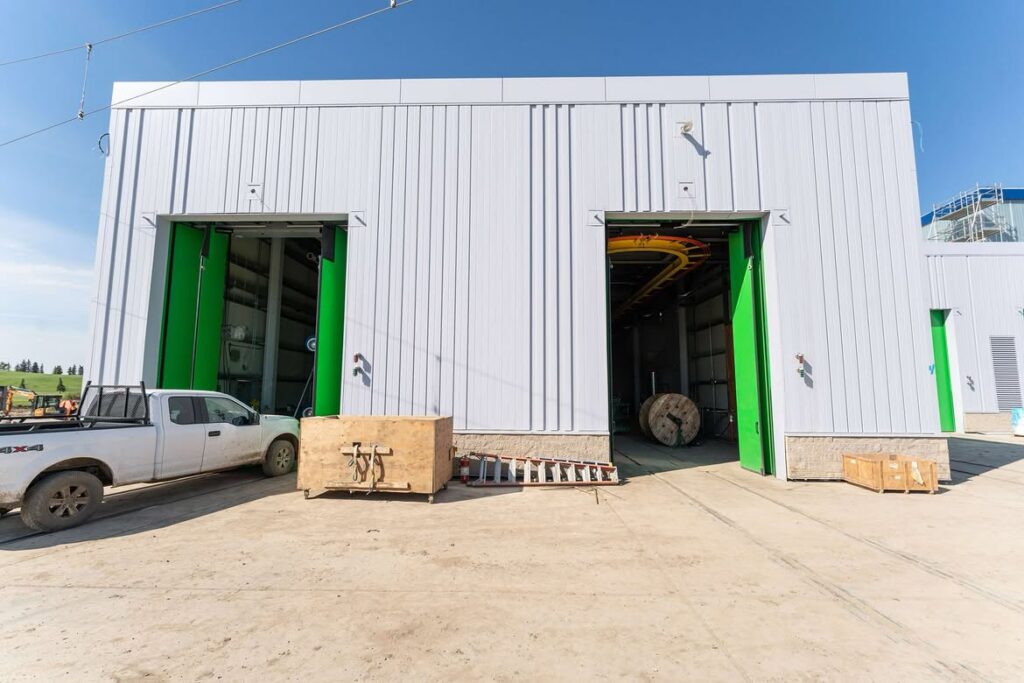 Gerry Wright LRT Facility in Edmonton featuring two opened &amp; green commercial bi-fold doors installed for transit infrastructure operations.